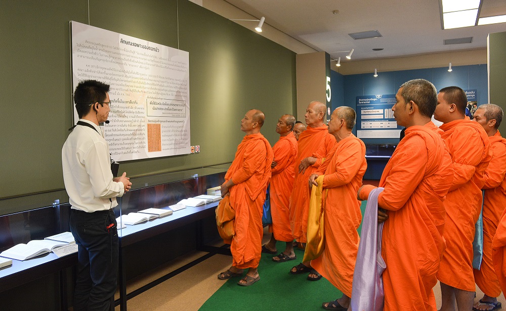 身穿橘色袈裟的僧侣们正在参观《法华经》展。