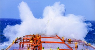 Gran ola golpeando la proa de un barco.