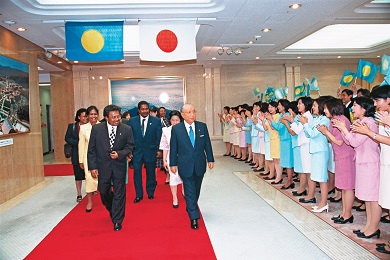 A delegation walking through a large room greeted by a crowd of people clapping