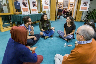Un pequeño grupo de personas sentadas en el suelo dialoga en círculo