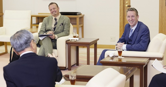 Three men seated in chairs having a lively conversation