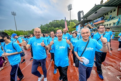 一群男士穿著印有「Act Now」（即刻行動）字樣的藍色T恤，在運動場的跑道上笑著對鏡頭比讚。