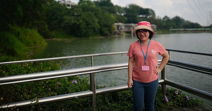 张晶惠站在湖水前摆出姿势照相。