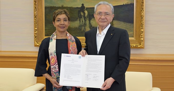 Two people standing side-by-side holding a signed contract.