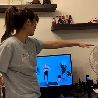 Woman following along with an exercise routine on a computer screen.