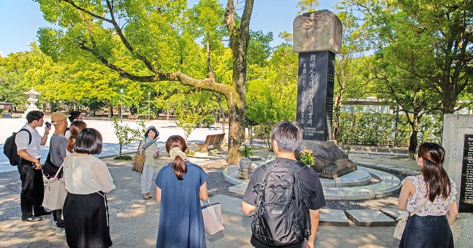 People standing around a monument in a park.