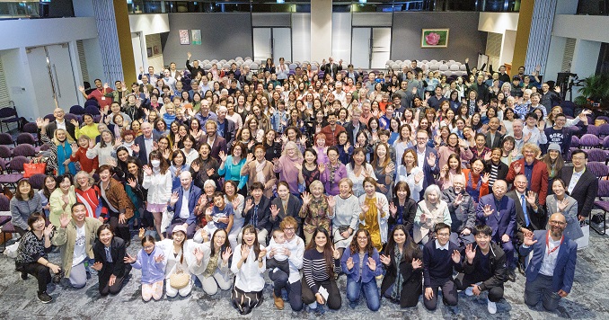 A group of people taking a commemorative photo in a large hall.