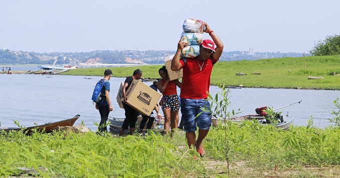 A group of men carrying relief supplies from a boat and walking inland.