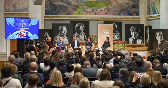 People seated in a hall listening to a panel discussion.