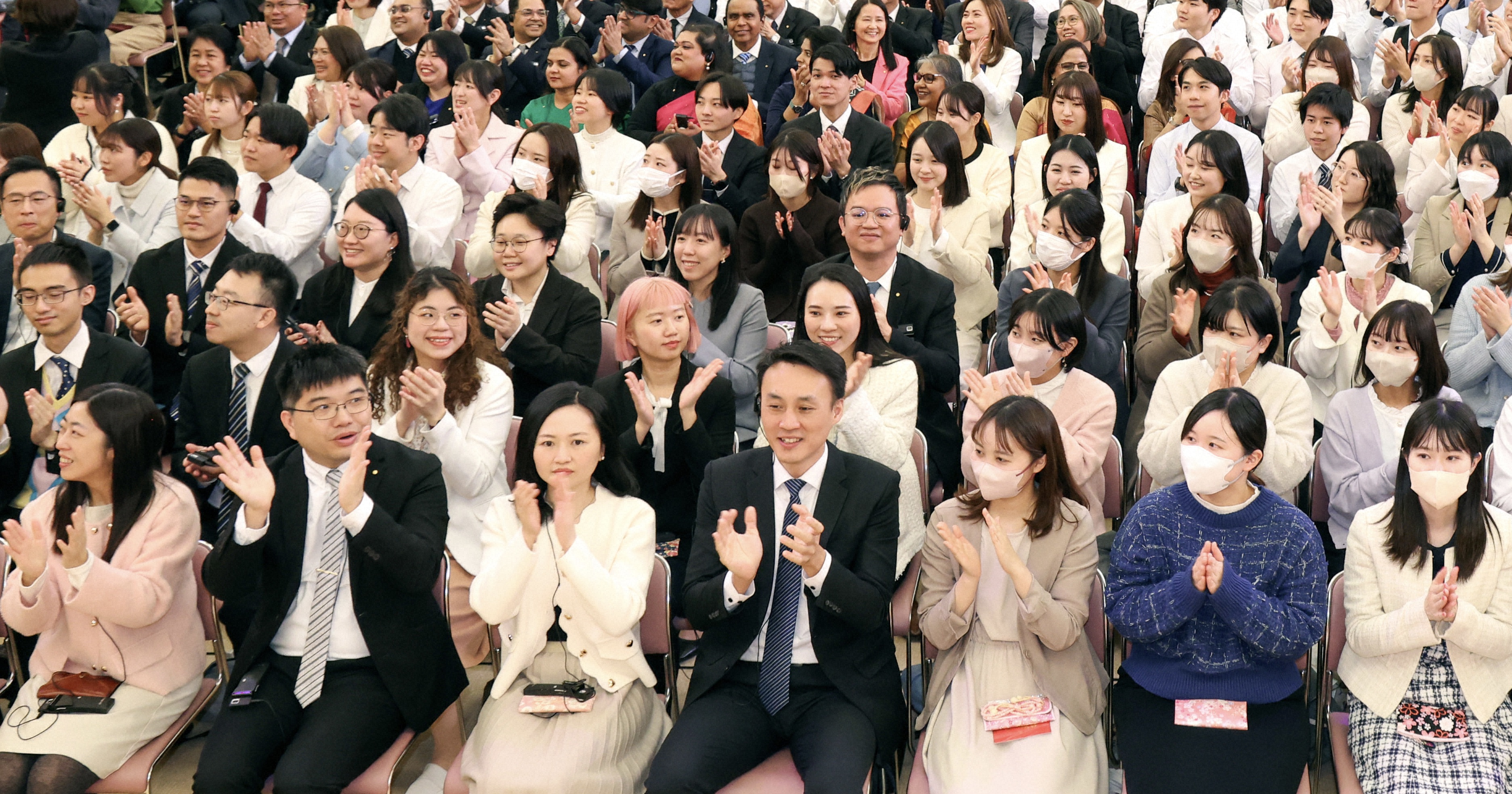 People sitting in an auditorium, applauding.