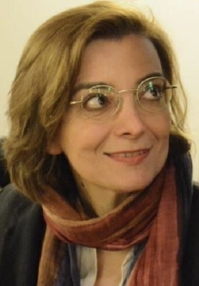 Woman with glasses, looking up and smiling.