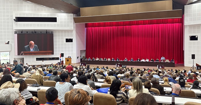 People seated in an auditorium facing a panel of speakers.