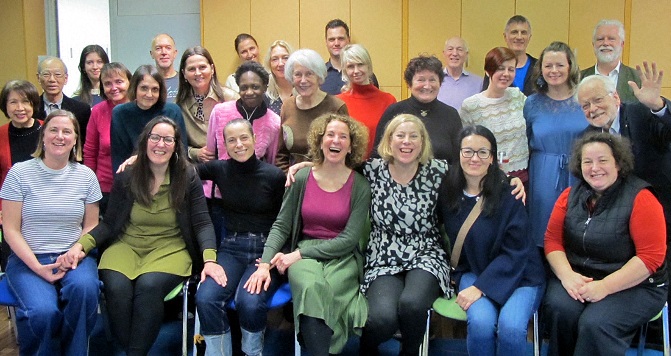 Group of smiling people posing for a photo; a row of seated people at the front.