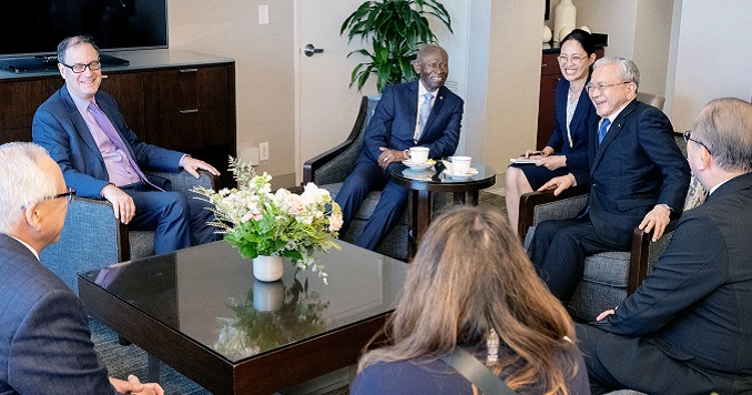People in conversation, smiling as they sit together a around a coffee table.
