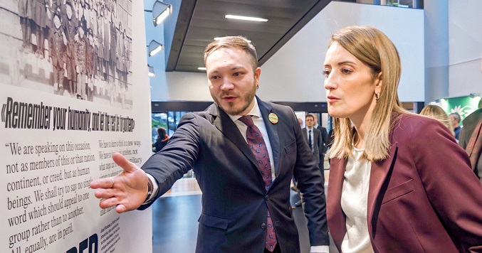 A person presenting an exhibition panel on nuclear disarmament to a public figure.