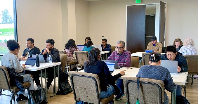 People sitting at tables using computers in a classroom.