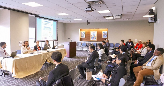 Four people seated at a table in a conference room.
