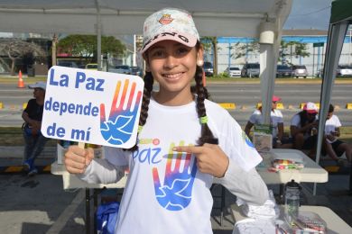 A young girl poses with a sign in Spanish that reads “Peace depends on me” at the event venue