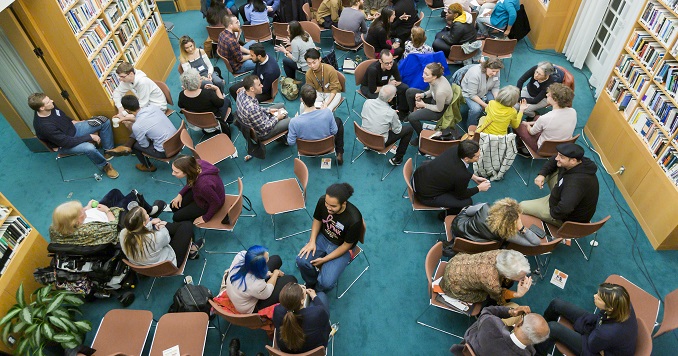 An aerial view of small groups of people in dialogue in a hall