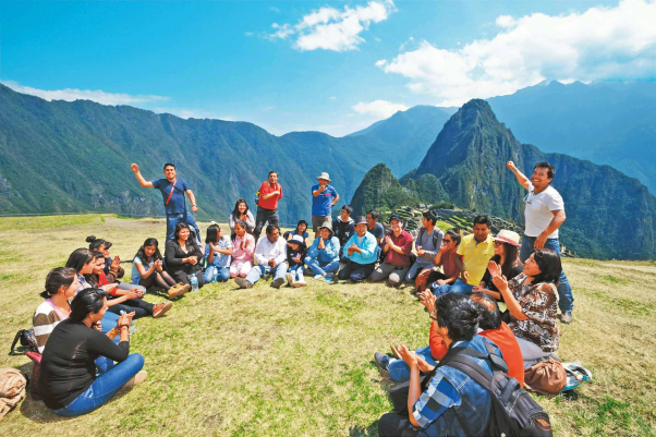 A group of people sitting in a circle on an open mountain top 